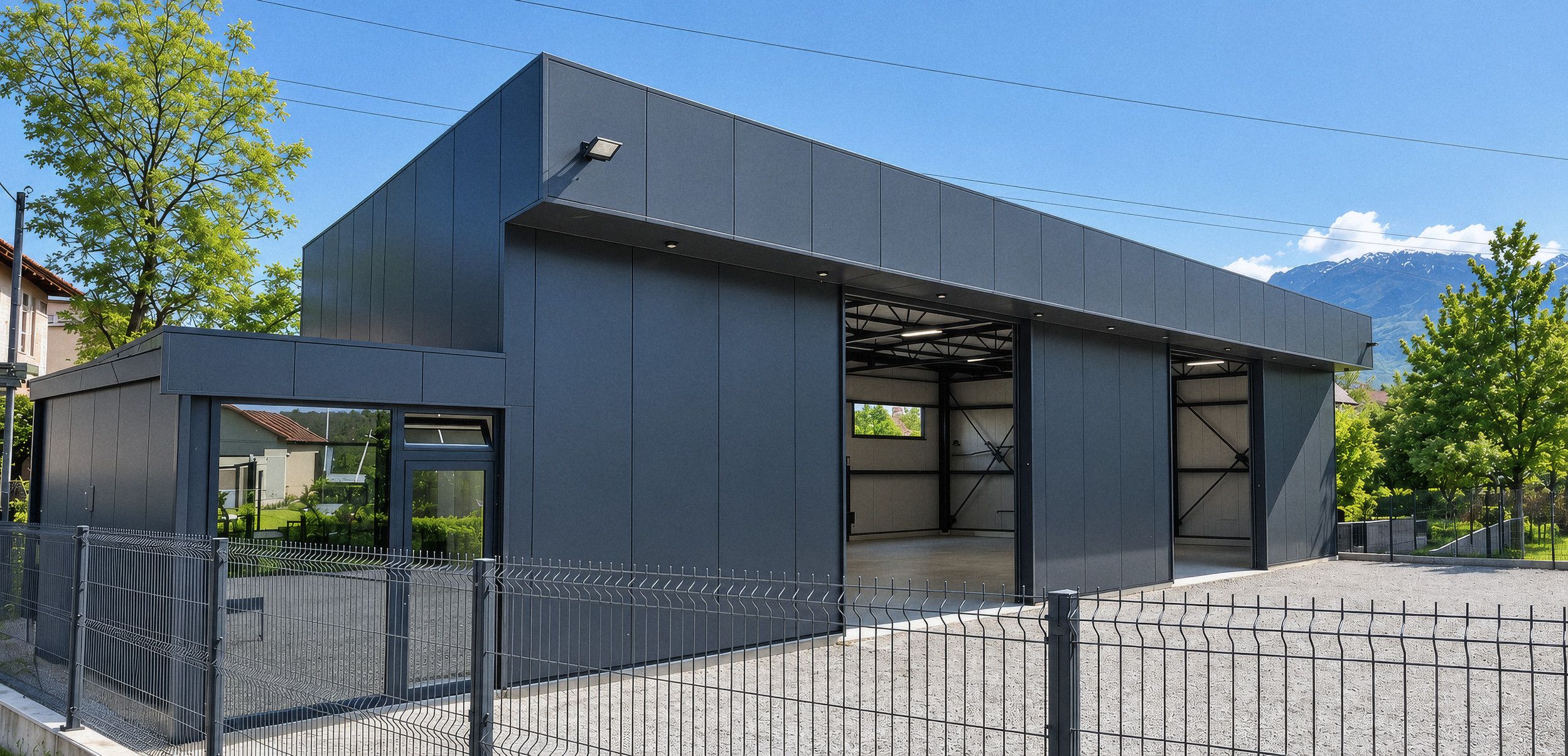 Eingang der Werkstatt von Latifi Metal in Peja: ein Stahlbau mit anthrazitfarbener Paneelbekleidung, geöffneten Werkstatttoren und Bergen im Hintergrund.